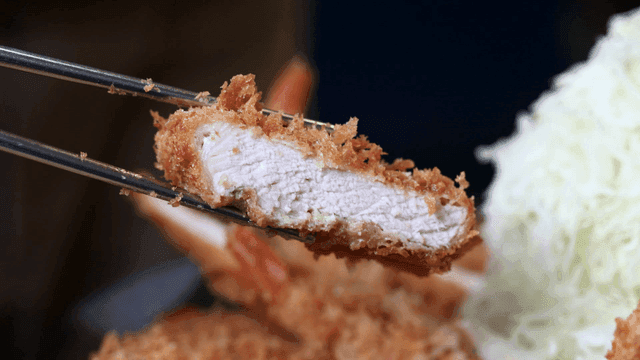 Chopsticks picking up crispy pork cutlet