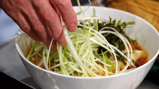 Adding seasoned green onions to ramyeon with seaweed