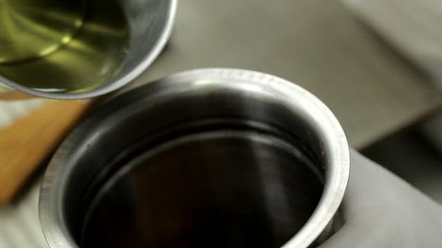 금속 용기에 기름을 붓는 장면