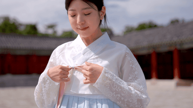 한복을 입은 여성이 저고리를 묶는 모습