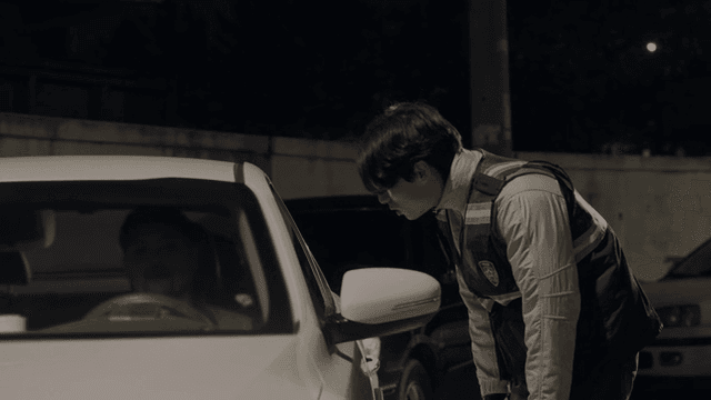 Police officer checking a car at night