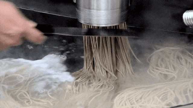 Extruding noodles into boiling water by machine