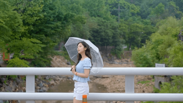 비 오는 날 우산을 쓰고 걷는 여성