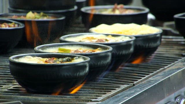 Several bowls of Korean beef and rice soup cooked on the stove in the restaurant kitchen