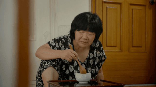An elderly woman eating alone indoors