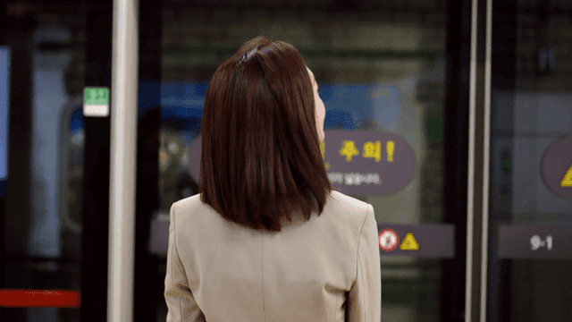 Back view of female office worker waiting on subway platform