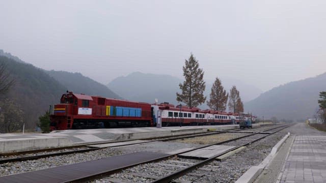 Red train at a quiet mountain station on a foggy day