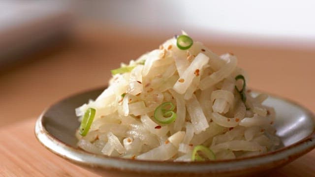 Radish side dish in ceramic bowl on wooden table