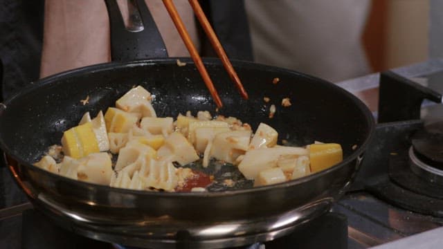 Frying bamboo shoots with chopsticks in a frying pan with oil