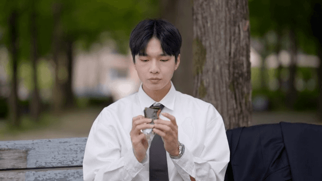 Office worker sitting on a park bench eating a quick lunch