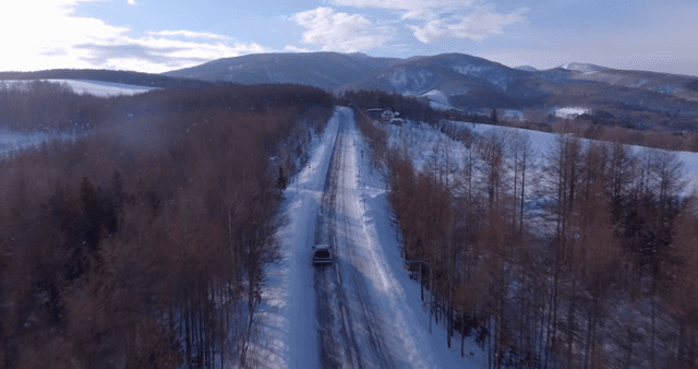 Snowy road winding through a forest