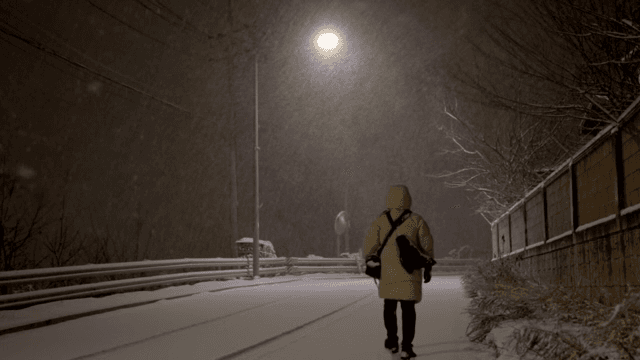 밤에 눈이 내리는 거리를 홀로 걷는 사람