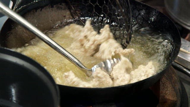 Frying meat in hot oil in a wok in the kitchen