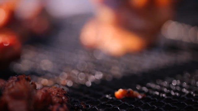 Grilling marinated pork ribs on a grill over burning charcoal