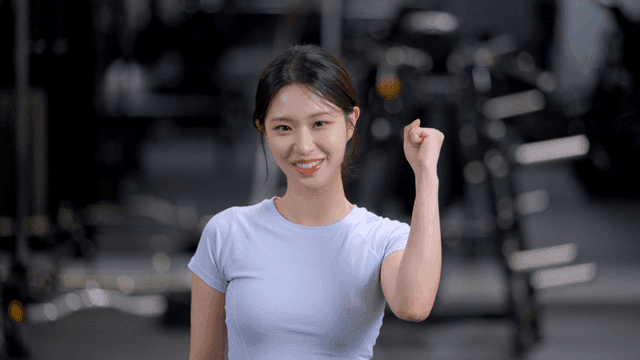 헬스장에서 정면을 보고 주먹을 모아 화이팅하는 젊은 여성
