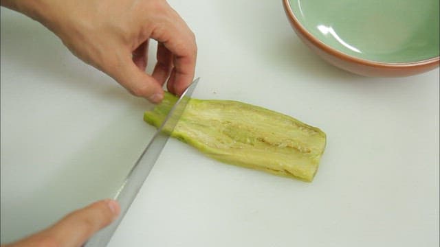 Slicing a cooked eggplant on a cutting board