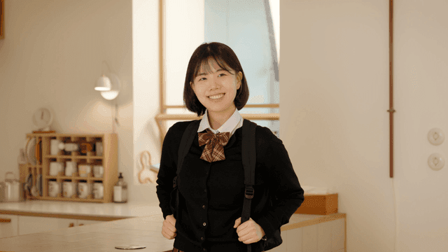Smiling schoolgirl carrying bag in bright house