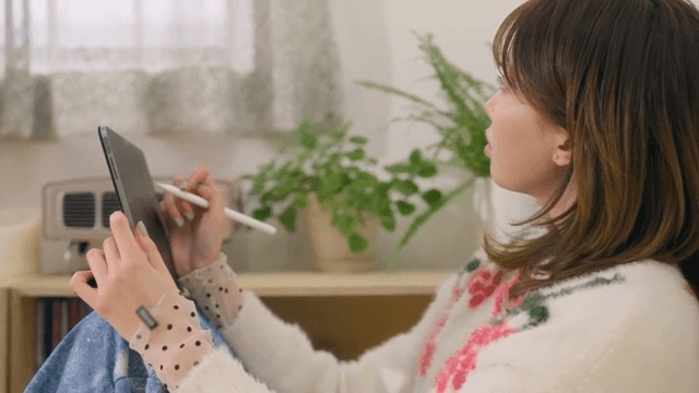 아늑한 방에서 태블릿을 사용하며 창문을 바라보는 여성