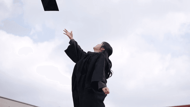 Graduates celebrating by throwing their graduation caps into sky