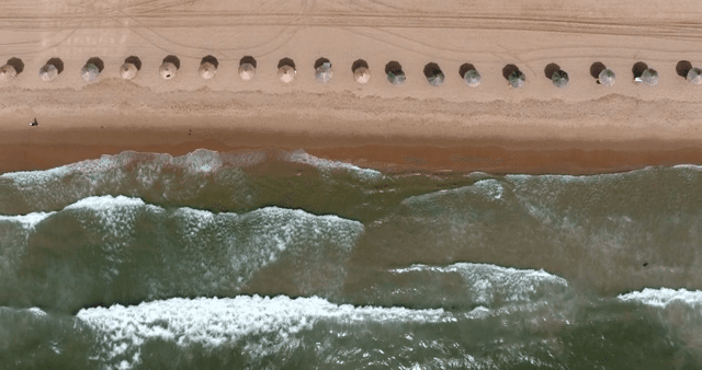A serene beach with umbrellas and waves