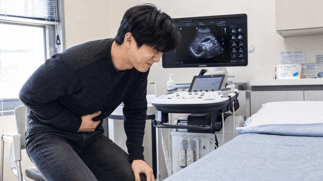 Man clutching his stomach in pain at medical clinic