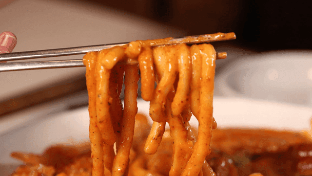 Spicy udon noodles picked up with chopsticks