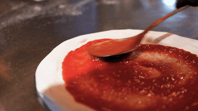 Tomato sauce spread on pizza dough