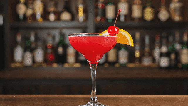 Fancy red cocktail with cherry and orange garnish