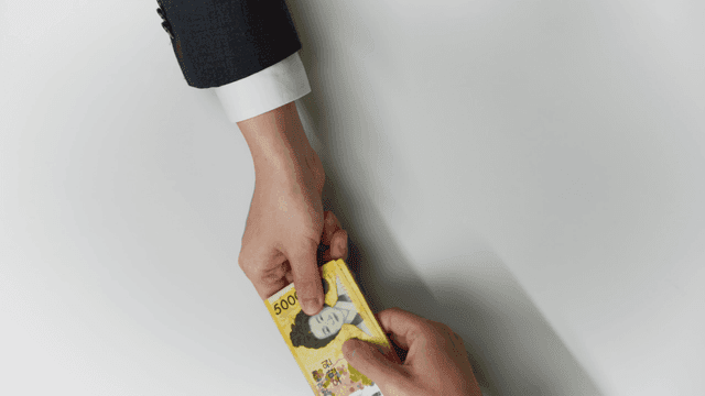 Hands exchanging Korean and Japanese currency