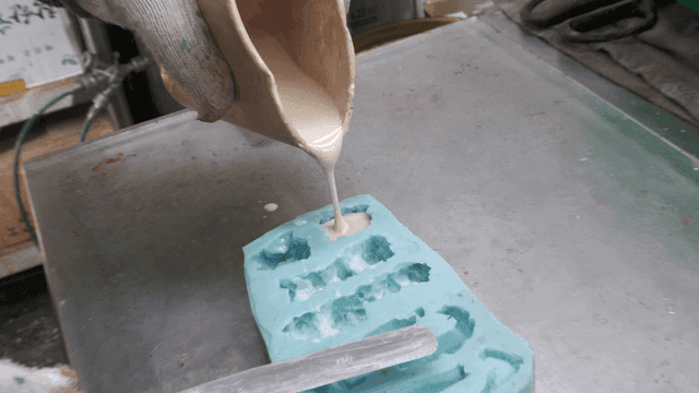Pouring silicone liquid into mold in workshop