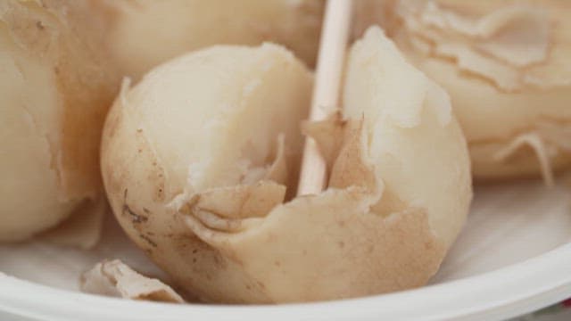 접시에 올려진 삶은 감자 껍질 벗기기