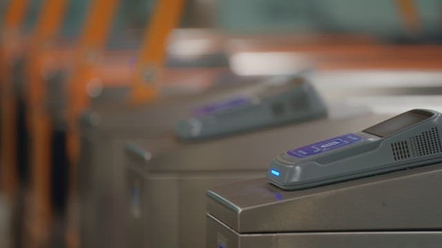 People using card readers at subway turnstiles