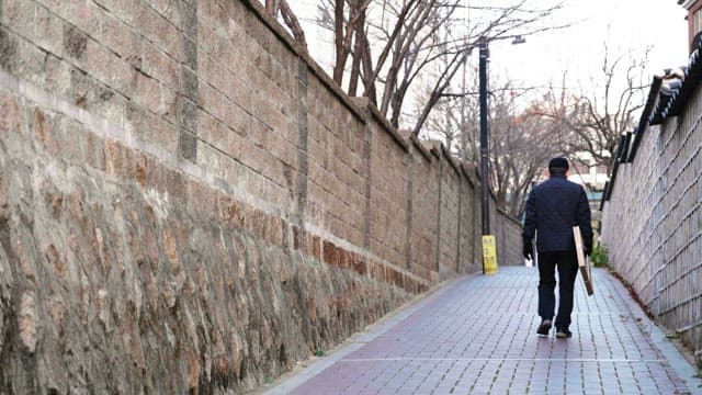 People with backpacks on their backs walking down a narrow alley between stone walls