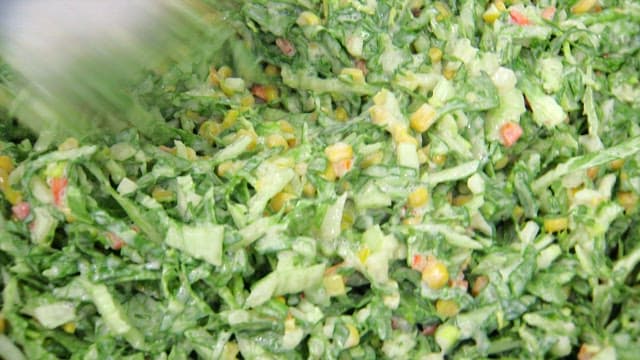 Fresh spring cabbage coleslaw being mixed with dressing