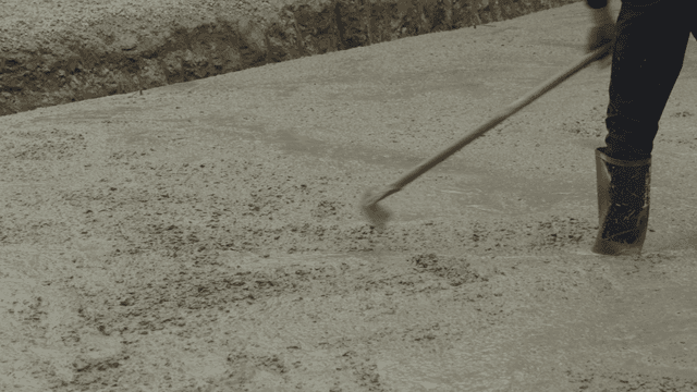 작업자가 갈퀴로 젖은 콘크리트를 고르는 모습