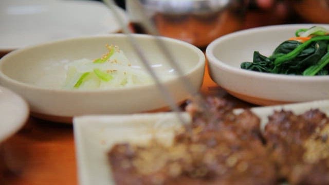 반찬과 밥이 있는 테이블위에서 집어 먹는 떡갈비