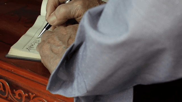 노트에 글을 쓰는 노인