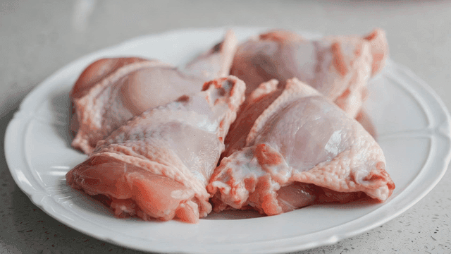 Raw chicken pieces on a white plate