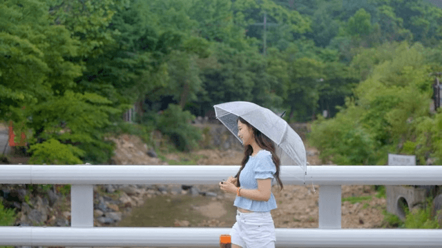 비 오는 날 우산을 쓰고 걷는 여성