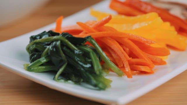 흰 접시에 채 썰려 담긴 신선한 채소와 구운 고기