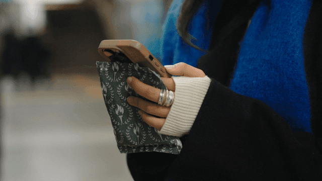 Woman using a hot pack and smartphone on the subway
