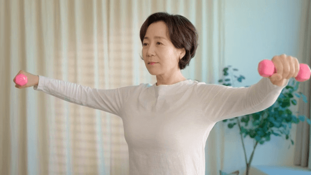 실내에서 덤벨 운동하는 여성