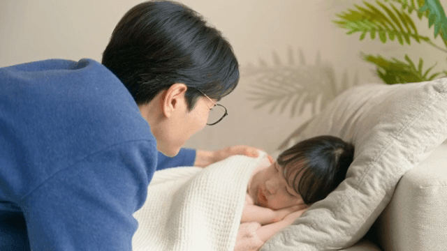 Father gently caressing her sleeping child
