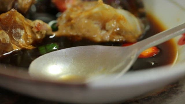 Spoonful of rich soy sauce marinated crab soup in a bowl