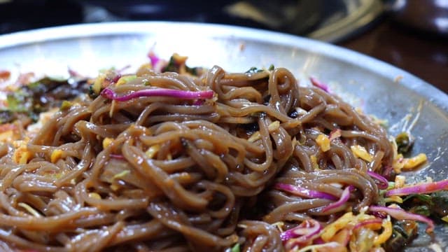 먹음직스러운 돼지고기 수육을 얹어 먹는 메밀면 한 젓가락