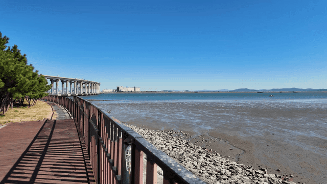 A coastal walkway with a distant bridge