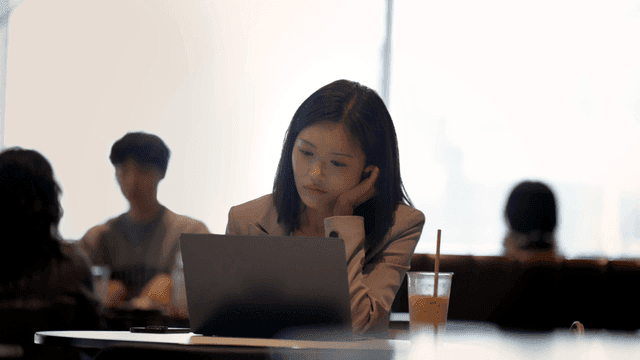 Female office worker looking at laptop in cafe with people