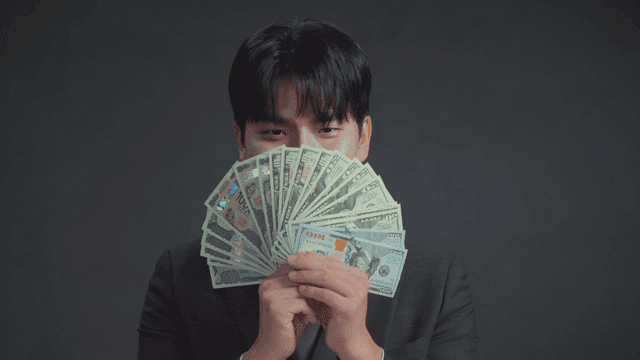 미소를 지으며 달러를 들고 있는 남자