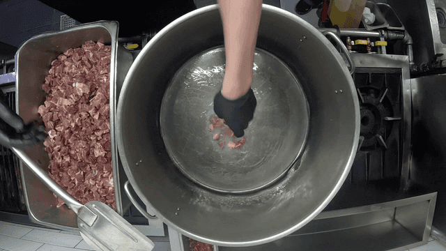 Pieces of raw meat submerged in oil in large pot
