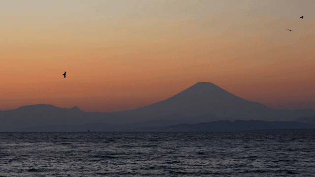 Calm sea with mountains visible at sunset